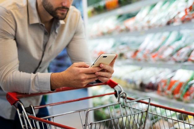 Homem brincando com seu telefone no supermercado