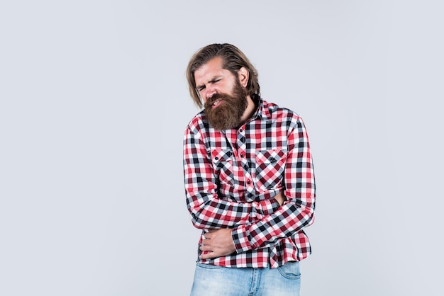 Homem brutal sentindo dor de saúde masculina de casco no estômago hipster maduro com barba tem dor de estômago cara caucasiano brutal com bigode homem barbudo usa camisa quadriculada cópia espaço