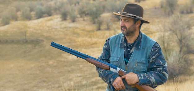 Homem caçador camuflado com uma arma durante a caça em busca de pássaros selvagens ou caça no outono
