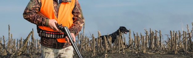 Homem caçador camuflado com uma arma durante a caça em busca de pássaros selvagens ou caça no outono