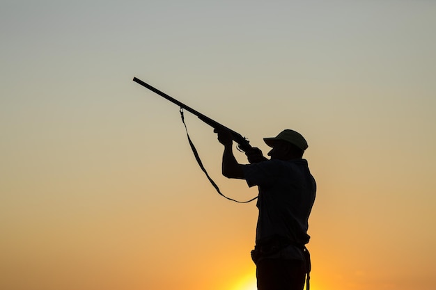 Homem caçador camuflado com uma arma durante a caça em busca de pássaros selvagens ou de caça.