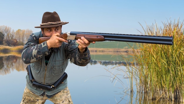 Homem caçador camuflado com uma arma durante a caça em busca de pássaros selvagens ou de caça
