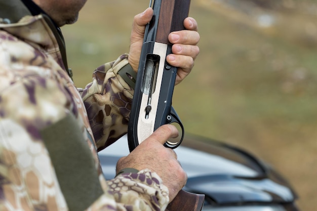 Homem caçador camuflado com uma arma durante a caça em busca de pássaros selvagens ou de caça