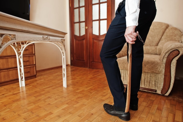 Homem calça sapatos pretos clássicos com uma colher de sapato de madeira