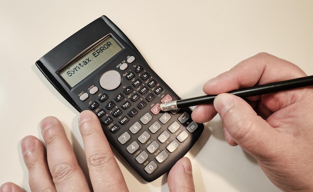 Homem calculando em calculadora científica preta com texto de erro sntax no ecrã