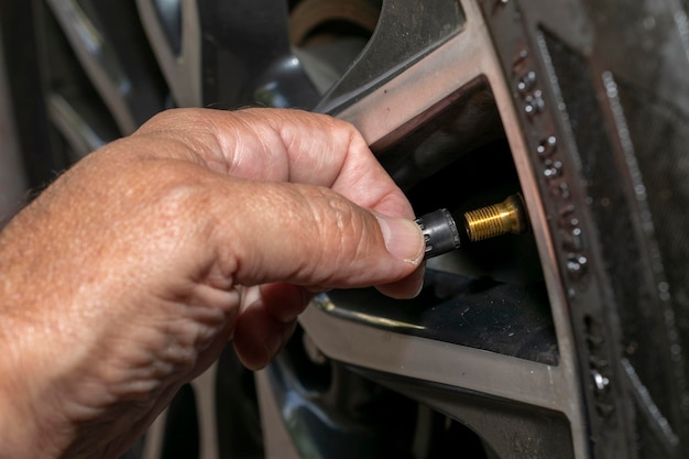 Homem calibrando a manutenção preventiva do pneu do carro