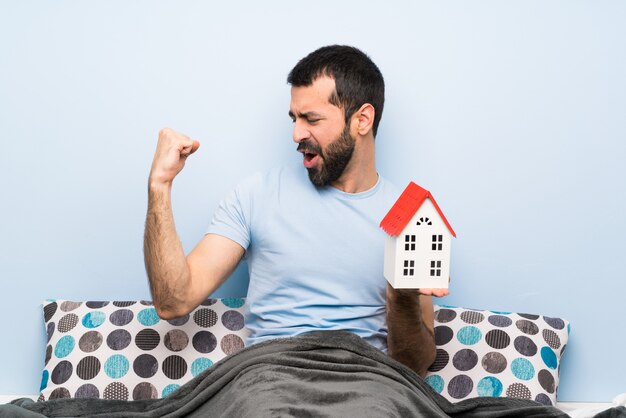 Foto homem, cama, barba, segurando, pequeno, casa