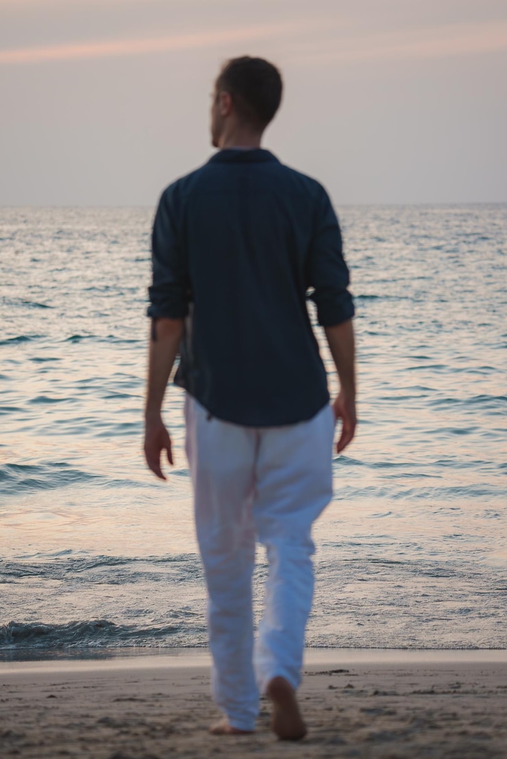 Foto homem caminhando descalço em uma praia serena ao pôr-do-sol na tailândia