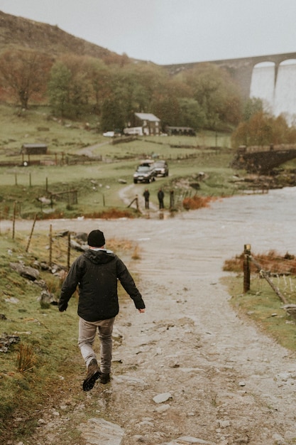 Homem caminhando em direção a seus amigos no campo com estrutura de barragem