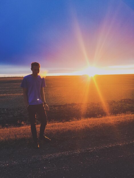 Foto homem caminhando na estrada contra o céu nublado durante o pôr do sol