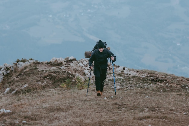 Homem caminhando nas montanhas do pôr do sol com mochila pesada Soma do conceito de aventura de desejo de viajar Estilo de vida de viagem