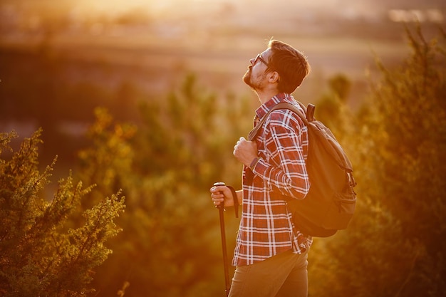 Homem caminhando nas montanhas do pôr do sol com mochila