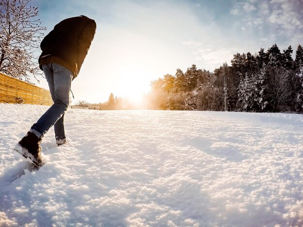 Homem caminhando no campo coberto de neve contra o céu