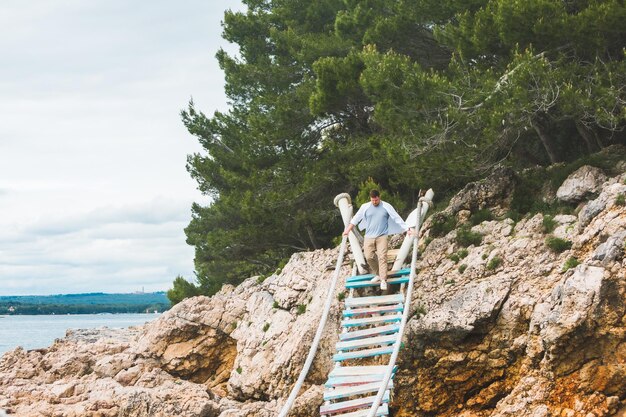 Homem caminhando pela ponte pênsil cruzando o mar adriático, horário de verão