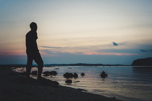 Homem caminhando silhueta no pôr do sol das montanhas e oceano