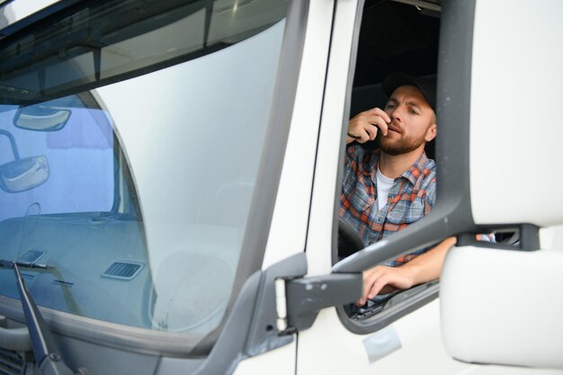 Foto homem caminhoneiro dirigindo em uma cabine de seu caminhão e falando no transmissor de rádio