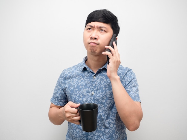 Homem camisa azul falando com telefone celular e segurando a xícara de café sente tensão