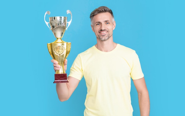 homem campeão feliz comemora prêmio da vitória isolado em azul homem campeão comemora vitória com prêmio no estúdio homem campeão comemora prêmio vitória foto do homem campeão comemora vitória