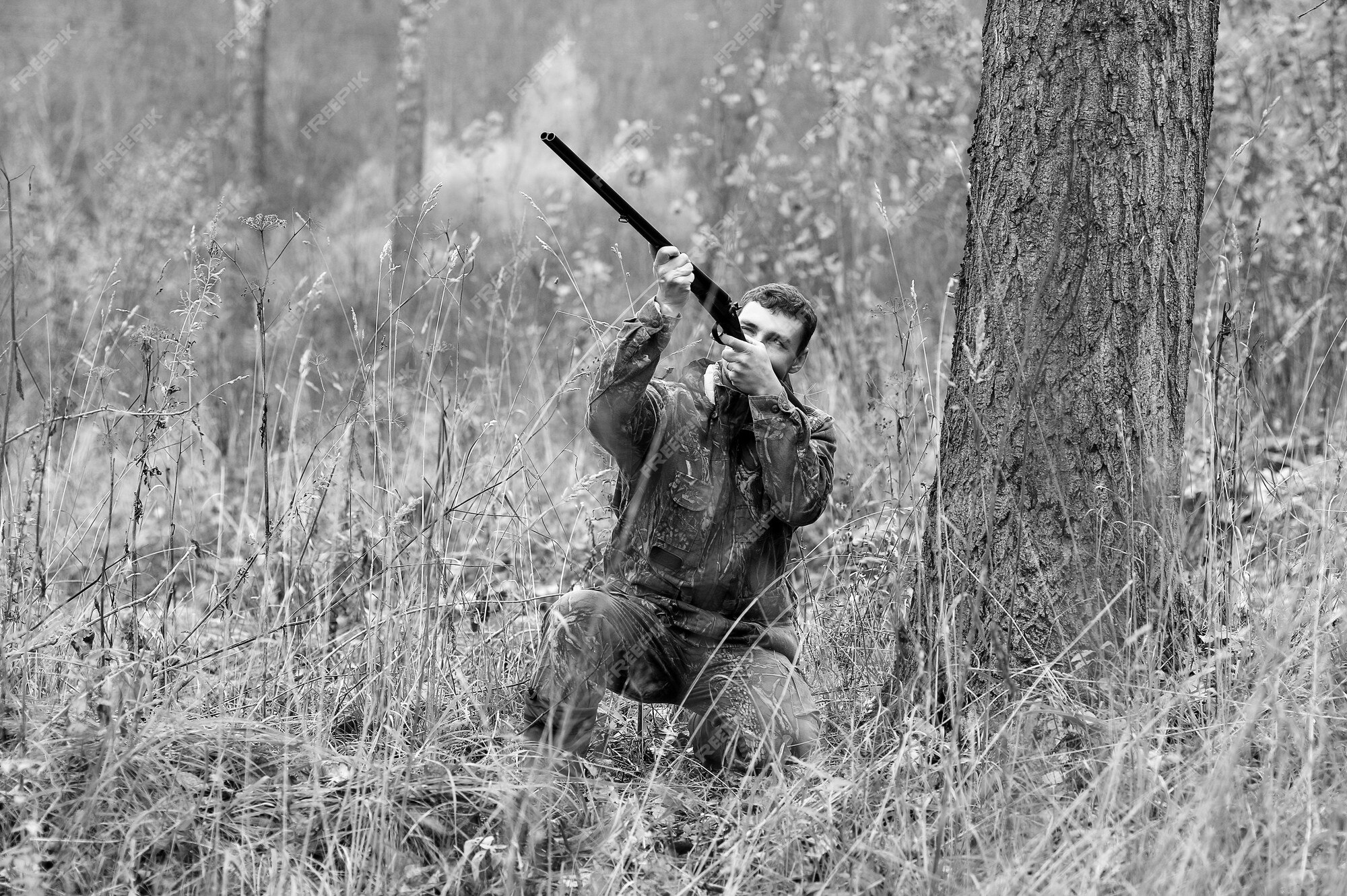 O caçador mira com um rifle. um homem camuflado está se preparando para  atirar. caçando na floresta com um rifle de precisão