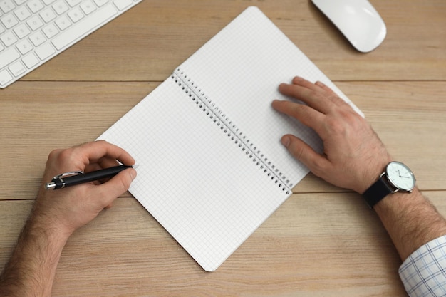 Homem canhoto escrevendo no caderno na vista superior da mesa de madeira