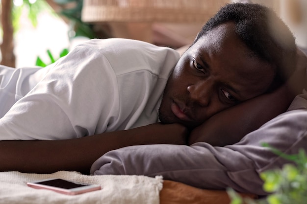 Homem cansado africano não consegue dormir de insônia tentando descansar