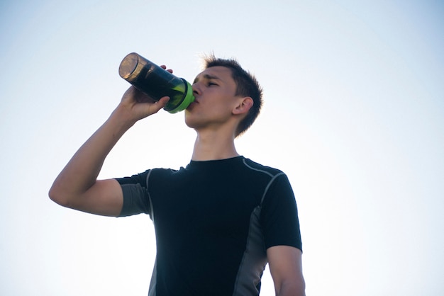 Homem cansado atleta beber água de um shaker