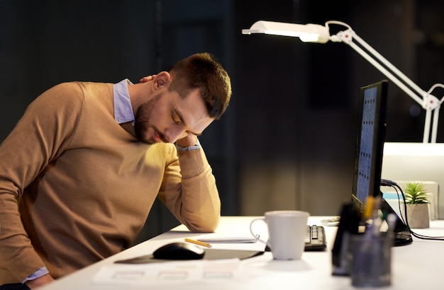 Foto homem cansado com dor no pescoço trabalhando no escritório à noite