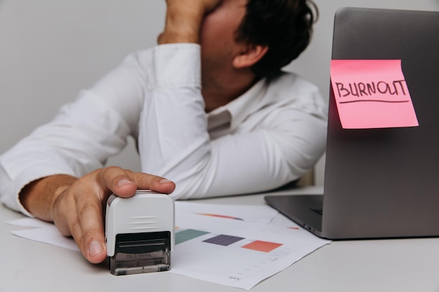 Foto homem cansado usa um selo do conceito de síndrome de burnout da organização