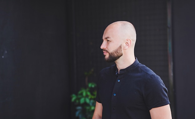 Homem careca e brutal com barba posando com uma camiseta