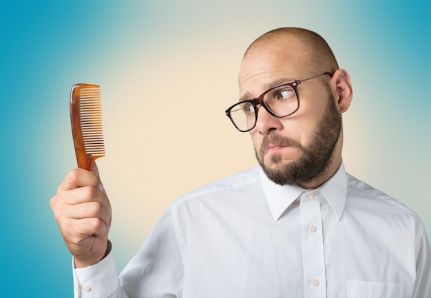 Homem careca infeliz segurando o pente