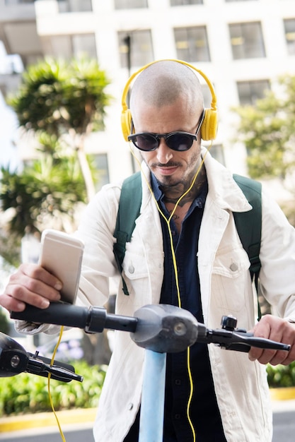 Homem careca levando uma scooter pública na cidade