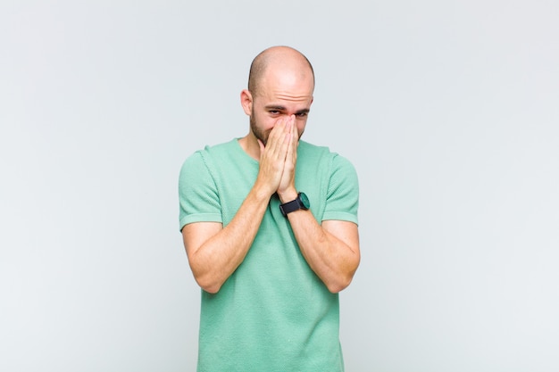 Homem careca preocupado, esperançoso e religioso, orando fielmente com as palmas das mãos pressionadas, implorando perdão