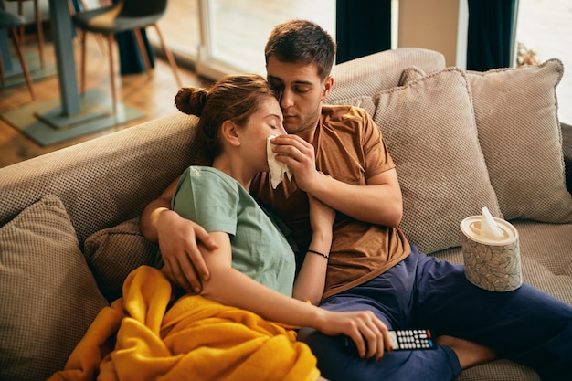 Homem carinhoso enxuga as lágrimas da namorada enquanto assiste filme triste na TV em casa