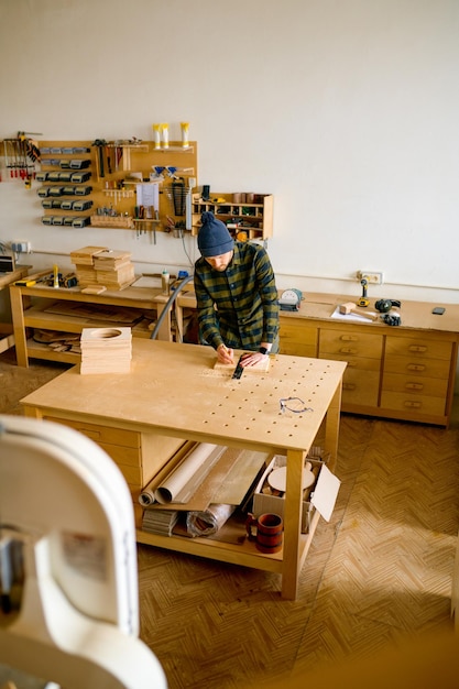 Foto homem carpinteiro fazendo desenho técnico com lápis e régua em tábua de madeira diy e conceito de oficina de carpintaria