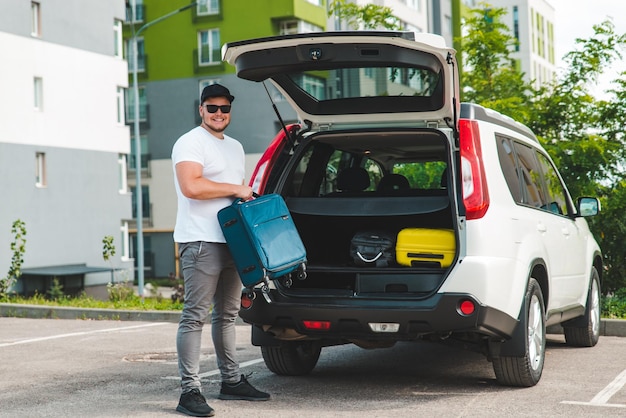 Homem carrega malas no porta-malas do carro pronto para viagem de carro