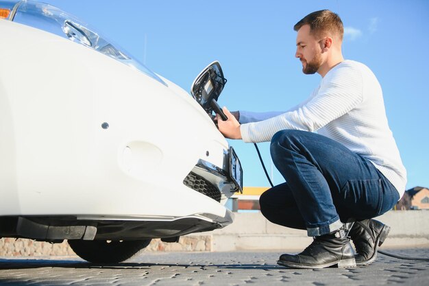 Homem carrega um carro elétrico na estação de carregamento