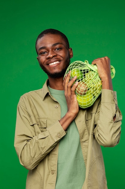 Foto homem carregando bolsa de malha com frutas verdes