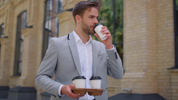 Homem carregando copos de papel com café quente para o escritório Gerente bebendo chá em movimento