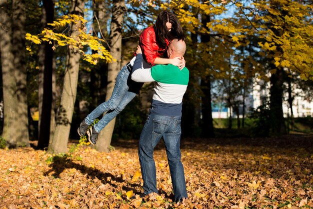 Homem carregando mulher cavalgando pela floresta de outono