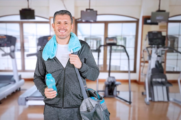 Homem carregando uma bolsa de ginástica e uma garrafa na academia