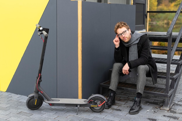 Foto homem casual posando ao lado de sua scooter elétrica