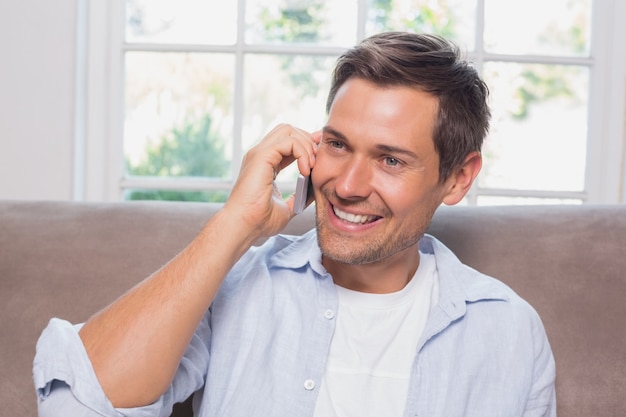 Homem casual usando o telefone móvel no sofá