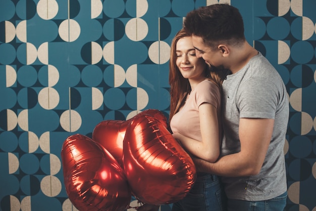 Foto homem caucasiano a abraçar a mulher e a dar-lhe balões num encontro a sorrir juntos