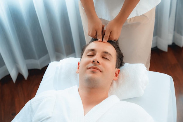 Homem caucasiano a desfrutar de uma massagem relaxante anti-estresse na cabeça.