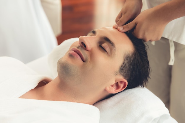 Homem caucasiano a desfrutar de uma massagem relaxante anti-estresse na cabeça.