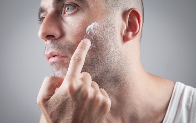 Homem caucasiano, aplicando creme facial.