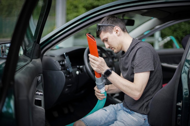 Homem caucasiano aspirando um carro em um posto de gasolina