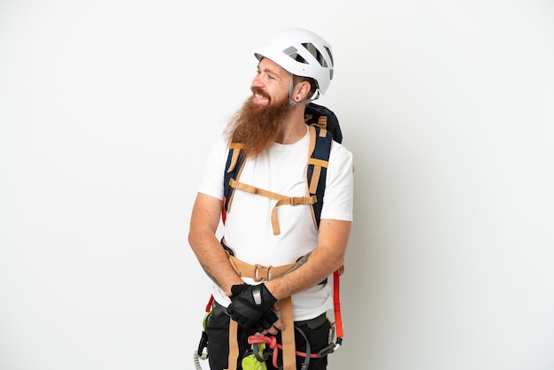 Homem caucasiano avermelhado jovem alpinista isolado no fundo branco olhando para o lado e sorrindo