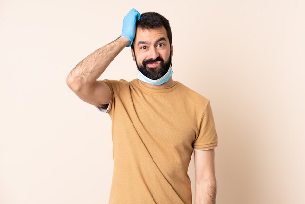 Homem caucasiano com barba, protegendo com uma máscara e luvas por cima do muro com uma expressão de frustração e não compreensão