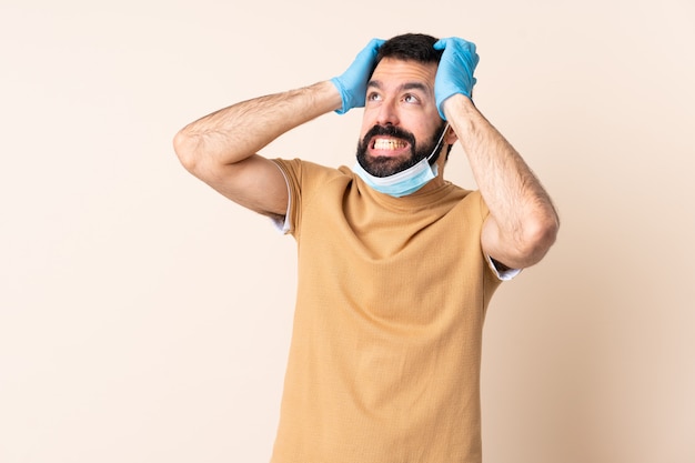 Homem caucasiano, com barba, protegendo com uma máscara e luvas sobre parede estressado oprimido